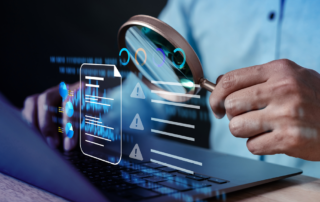 Person on laptop holding magnifying glass over alert data